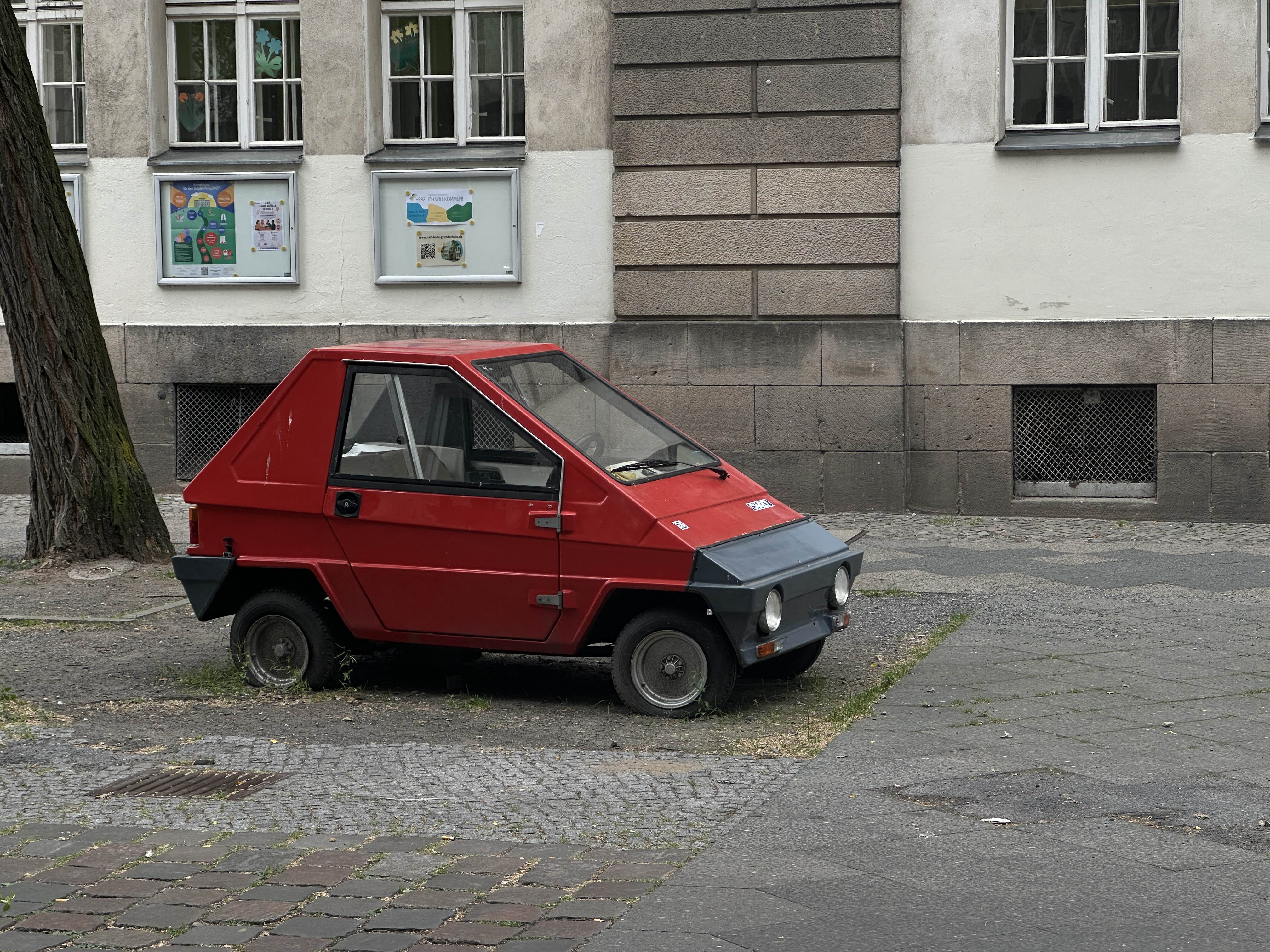A photo of tiny red car, with just one seat.